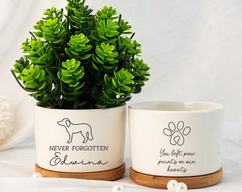 May include: Two white ceramic planters with bamboo saucers. One features a dog silhouette and the text "NEVER FORGOTTEN Edwina". The other has a paw print and the text "You left paw prints on our hearts". A green plant sits in one.
