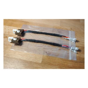 Può includere: Due cablaggi automobilistici con più fili e connettori colorati. I cablaggi hanno guaine intrecciate nere e sono confezionati in sacchetti di plastica trasparente. I connettori sono marroni e bianchi.