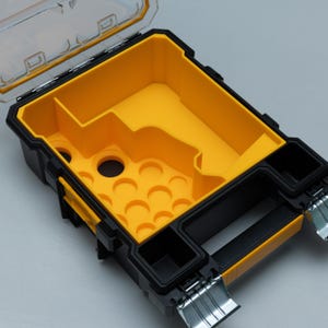 May include: Open, black and yellow tool organizer with a clear lid. The interior is bright yellow with various compartments and curved slots. The organizer has a black handle and metal hinges.