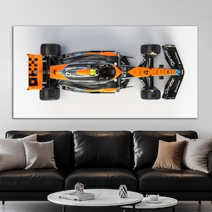 May include: Overhead view of a Formula 1 race car, mainly orange and black, with the number 4 displayed. The car features large tyres and aerodynamic elements. The word "Chrome" is visible on the rear wing.