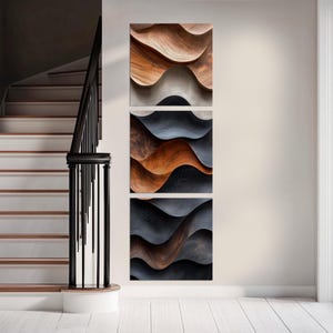 a modern art piece with three panels, each depicting a different color gradient, mounted on a white wall next to a staircase.