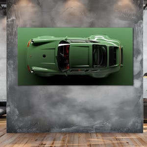 May include: An overhead view of a green vintage car print on a green background. The car has a sleek design with visible windows and red interior details. The artwork is mounted on a gray concrete wall above a wooden floor.