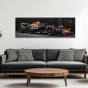 May include: A framed canvas print of a Formula 1 race car. The car is primarily dark blue with red and yellow accents, and features the Oracle and Mobil logos. The car is in a garage setting.