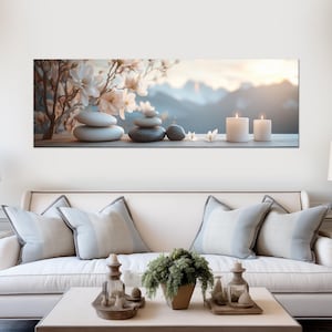 May include: A serene image features stacked stones, white candles, and delicate flowers, evoking a sense of tranquility. The background showcases a blurred mountain landscape. The scene is set on a wooden surface, creating a calming aesthetic.