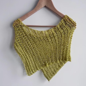 May include: A chartreuse-colored, open-weave top hangs on a wooden hanger against a white background. The top has a unique asymmetrical design with a diagonal hemline. The knitted fabric has a net-like appearance.