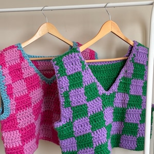 Könnte beinhalten: Zwei ärmellose Häkeltops mit einem karierten Muster. Ein Top ist pink und blau, das andere ist grün und lila.
