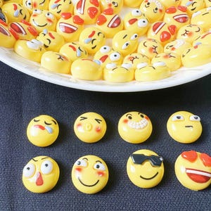 May include: A collection of yellow smiley face figurines with various expressions, including happy, sad, surprised, and winking. The figurines are arranged in a circle on a white plate.