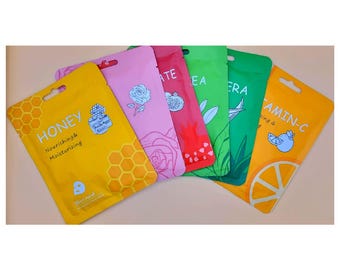 May include: A selection of face mask sachets in various colours. The packets are yellow, pink, red, green, and orange. Each sachet features a unique design, such as honeycomb, roses, pomegranate, leaves, and citrus fruit. Text on the packets includes "HONEY", "TEA", "ALOE VERA", and "VITAMIN-C".