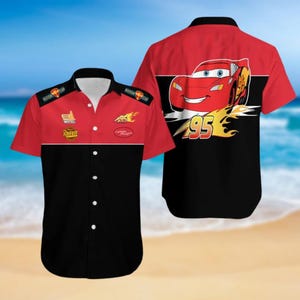 Könnte beinhalten: Kurzarm-Hemd mit Knöpfen in Rot, Schwarz und Gelb mit einem Cartoon-Bild eines roten Rennwagens mit der Nummer 95 an der Seite. Das Hemd trägt die Aufschrift "Piston Cup" und "Rust-eze".