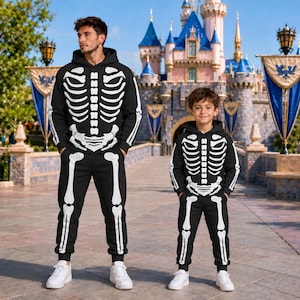 May include: Two matching black hooded sweatshirts and joggers sets featuring a white skeleton bone print on the front. The hoodies have long sleeves and the trousers have an elastic waistband and cuffs, creating a coordinated skeleton costume look.