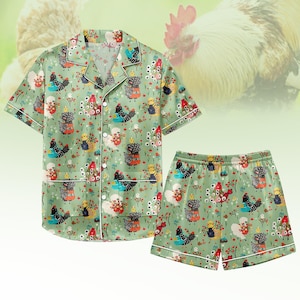 Könnte beinhalten: Ein zweiteiliges Pyjama-Set mit hellgrünem Hintergrund und einem sich wiederholenden Muster aus bunten Hühnern und floralen Akzenten. Das kurzärmelige Oberteil und die Shorts haben weiße Paspeln.