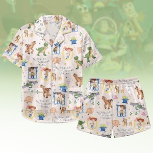 Könnte beinhalten: Zweiteiliger cremefarbener Pyjama-Set, bestehend aus einem Hemd mit Knöpfen und Shorts. Das Set ist mit einem sich wiederholenden Muster von Toy Story-Charakteren versehen. Das Hemd hat kurze Ärmel und einen Reverskragen. Die Shorts haben einen elastischen Bund.