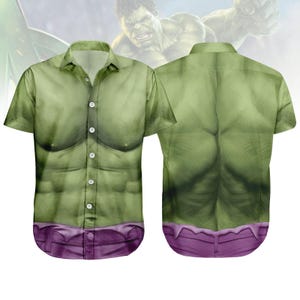 Puede incluir: Camisa verde de manga corta con un diseño estampado que imita el físico de Hulk. La camisa presenta una representación detallada del pecho y los músculos abdominales del personaje, con una cintura morada. El diseño es visible tanto en la parte delantera como en la trasera.