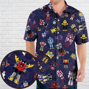 May include: Navy blue short-sleeved button-down shirt with a repeating pattern of colourful pixelated robots. The robots are in various poses and colours, including red, yellow, blue, and grey. The shirt has a classic collar and button closure.