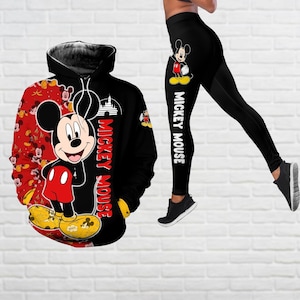 Puede incluir: Sudadera negra y roja con un gráfico de Mickey Mouse y el texto "Mickey Mouse". Leggings negros con un gráfico de Mickey Mouse y el texto "Mickey Mouse".