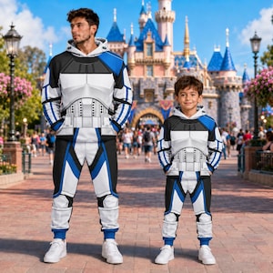 May include: A matching set of hooded sweatshirts and sweatpants featuring a white, black, and blue graphic print designed to resemble futuristic armor. The garments include long sleeves, hoods, and elasticized cuffs, showcasing a uniform pattern.