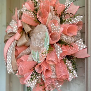 May include: A peach and brown wreath with a wooden sign that says "hello" and white polka dot ribbon.