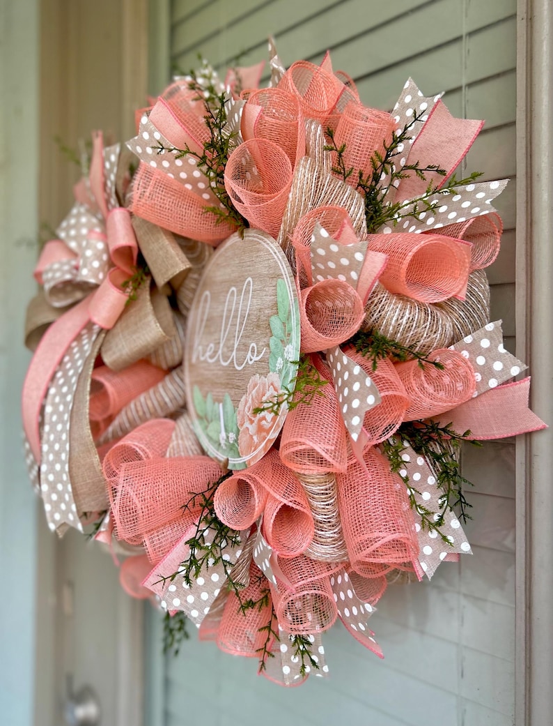 May include: A peach and brown wreath with a wooden sign that says "hello" and white polka dot ribbon.