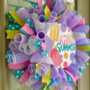 May include: A purple, white, pink, yellow, and teal mesh wreath with a round sign that says "hello summer" with a popsicle graphic.
