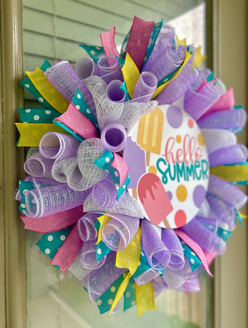 May include: A purple, white, pink, yellow, and teal mesh wreath with a round sign that says "hello summer" with a popsicle graphic.