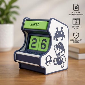 May include: A desk calendar shaped like a miniature arcade cabinet with a dark blue frame and white side panels. The side features a black graphic of a character and a mushroom. It displays the green text ENERO and the green numbers 26.