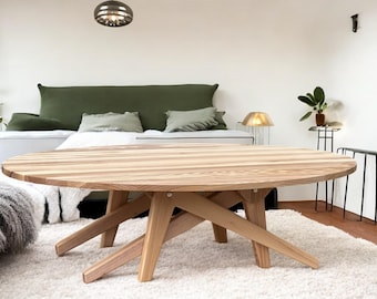 Può includere: Tavolino rotondo in legno chiaro con un design unico delle gambe. Il tavolo misura circa 122 cm di diametro e poggia su un tappeto bianco. La stanza presenta un letto con cuscini verdi e una lampada decorativa.