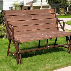 May include: A brown wooden bench with a metal frame that folds out to create a table. The bench is on a grassy lawn.