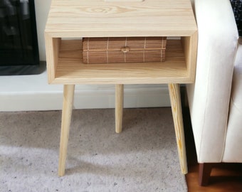 May include: A light wood end table with a shelf and four legs. The table has a woven basket on the shelf. The table is on a light gray rug.