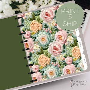 May include: A green and white planner with a floral design. The cover features a repeating pattern of pink, peach, and white flowers with green leaves. The planner has a ring binding and a tabbed divider with the words "PRINT & SHIP".