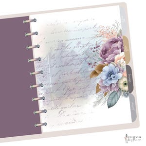 May include: A white planner with a floral design featuring purple, blue, and brown flowers. The planner has a purple cover and a silver coil binding. The text "Little Piece of My Planner" is printed on the bottom right corner of the planner.
