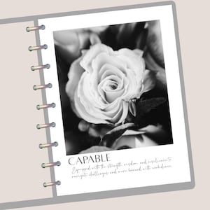 May include: Black and white photograph of a rose in full bloom, centered on a white page. The word "CAPABLE" is printed below the image, along with a motivational quote. The page is part of a notebook with silver spiral binding.