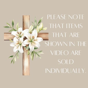 May include: A wooden cross adorned with white lilies and green leaves. The text "PLEASE NOTE THAT ITEMS THAT ARE SHOWN IN THE VIDEO ARE SOLD INDIVIDUALLY." is displayed on the right side of the image.