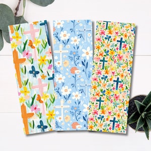 May include: Three floral bookmarks with cross designs. One bookmark has an orange cross with colorful flowers. Another has a light blue background with white flowers and crosses. The third has a colorful floral pattern with green crosses.