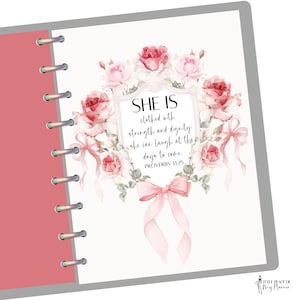 May include: A planner page with a floral design. The design features a wreath of pink and red roses surrounding a framed quote that reads "SHE IS clothed with strength and dignity: she can laugh at the days to come. PROVERBS 31:25". A pink bow is at the bottom.