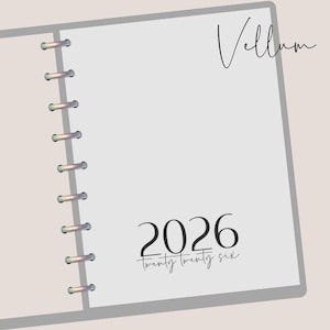 May include: Open notebook with a light gray cover and silver binding rings. The right page is white with the word "Vellum" in cursive at the top and the year "2026" in a bold font with "twenty twenty six" below it.