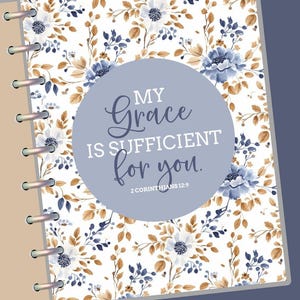 May include: A planner with a floral design featuring blue and white flowers, brown leaves, and the text "My Grace is Sufficient for you." The planner has a light brown cover and silver metal rings.