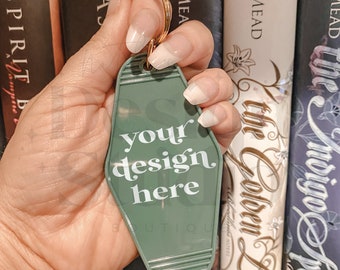 May include: A green motel key tag with a white inscription that reads "your design here". The key tag is attached to a gold key ring.