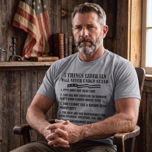 May include: A grey short-sleeved t-shirt featuring black text that reads 5 THINGS LIBERALS WILL NEVER UNDER STAND, followed by four numbered points about freedom, money, taxes, and financial responsibility, with a small American flag graphic.