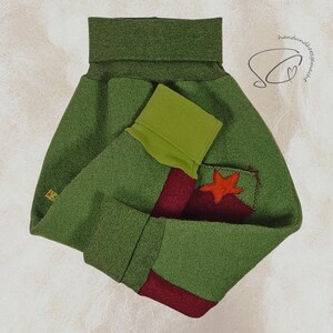 Pode incluir: Um aquecedor de pesco&ccedil;o de feltro verde com uma estrela vermelha aplicada em um bolso. O aquecedor tem um design de bloco de cores verde e vermelho. O item &eacute; feito &agrave; m&atilde;o.