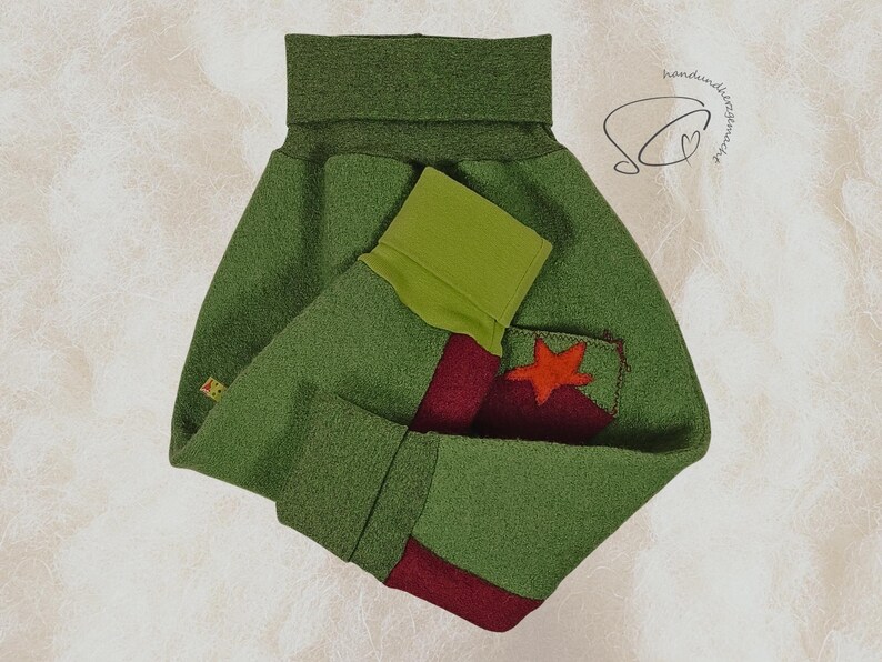 Pode incluir: Um aquecedor de pesco&ccedil;o de feltro verde com uma estrela vermelha aplicada em um bolso. O aquecedor tem um design de bloco de cores verde e vermelho. O item &eacute; feito &agrave; m&atilde;o.