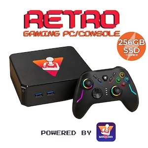 May include: A black retro gaming PC console with a joystick logo on top and two front USB ports. Includes a black wireless controller with colorful buttons, RGB lighting, and a 256GB SSD. The text reads RETRO GAMING PC/CONSOLE, POWERED BY BATOCERA.