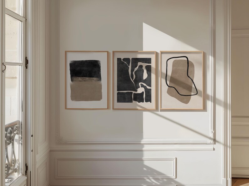May include: Three abstract art prints in black and beige frames. The prints feature abstract shapes and lines in black and beige.