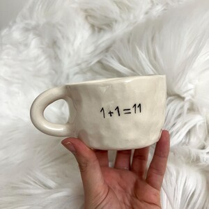 May include: A set of three ceramic mugs with a speckled, matte finish. Each mug is a different colour: light blue, cream, and grey. The mugs have a simple, modern design and a comfortable handle.