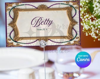 May include: A gold and purple table number card with a decorative frame and the text "Betty Table 1".