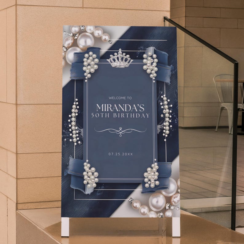 Puede incluir: Un letrero de cumplea&ntilde;os azul marino y blanco con el texto "Bienvenida al 50 cumplea&ntilde;os de Miranda" y la fecha "07.25.20XX". El letrero est&aacute; decorado con perlas, cintas y una corona.