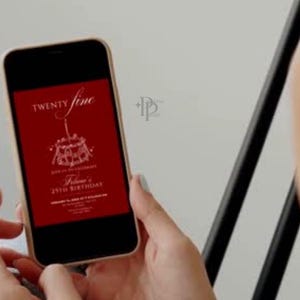 May include: A smartphone displays a red birthday invitation with white text. The invitation reads "Twenty Fine" above a cake illustration and "Felina's 25th Birthday" below. The phone is held in front of a light background.