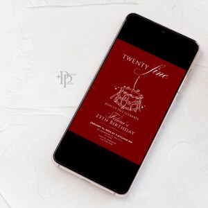 May include: A smartphone displays a birthday invitation with a deep red background. The invitation features the words "Twenty Fine" and "Felicia's 25th Birthday" in elegant white script, along with event details. The phone rests on a white surface.