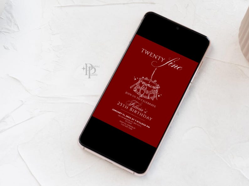May include: A smartphone displays a birthday invitation with a deep red background. The invitation features the words "Twenty Fine" and "Felicia's 25th Birthday" in elegant white script, along with event details. The phone rests on a white surface.
