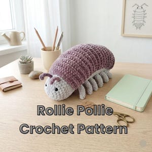 May include: A handmade crochet caterpillar toy in shades of purple and gray. The plush toy has a segmented body and small legs. The text "Rollie Pollie Crochet Pattern" is displayed below the toy.