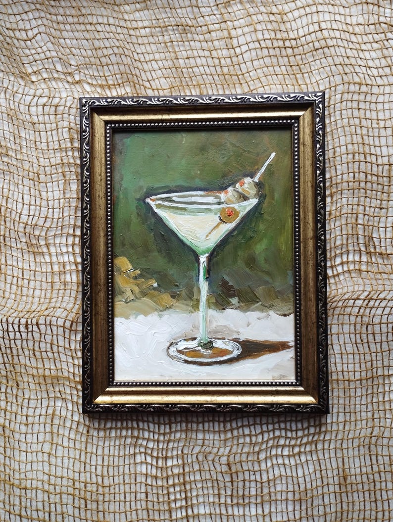 K&ouml;nnte beinhalten: Ein gerahmtes &Ouml;lgem&auml;lde eines Martini-Glases mit zwei gr&uuml;nen Oliven an einem Zahnstocher. Das Glas ist mit einer klaren Fl&uuml;ssigkeit gef&uuml;llt und steht auf einer wei&szlig;en Oberfl&auml;che. Der Hintergrund ist gr&uuml;n und braun.